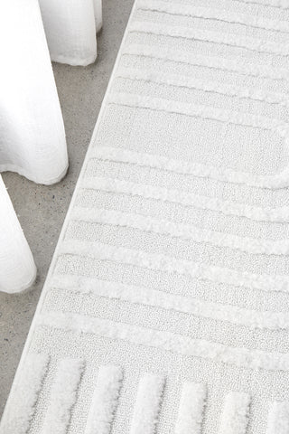 Close-up of a textured white rug on a neutral floor.