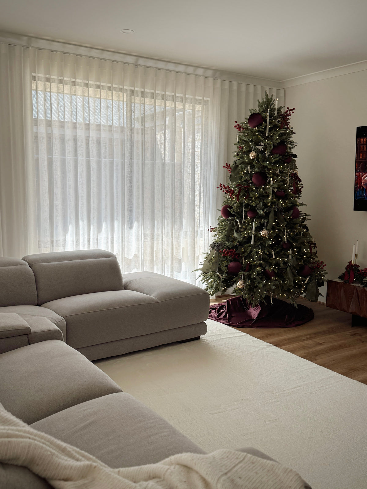 Living room with a decorated Christmas tree and beige sofa.